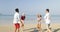 Two couples running on beach to water woman hold man hands happy cheerful people tourists on vacation