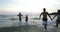 Two Couples Running From Water Sea Holding Hands, Young Friends Group On Beach At Sunset Having Fun Mix Race Men And