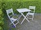 Two courtyard chairs and table in a secluded and private garden at home. Wooden patio furniture and seating area for