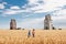 Two cowboy farmers walking in wheat field by elevators.