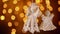 Two crochet christmas angel decorations hanging in front of blurry lights