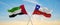 two crossed flags Chile and United Arab Emirates waving in wind at cloudy sky. Concept of relationship, dialog, travelling between