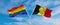 two crossed flags LGBT Pride and Belgium waving in wind at cloudy sky. Concept of relationship, dialog, travelling between two