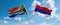 two crossed flags Republic Srpska and South Africa waving in wind at cloudy sky. Concept of relationship, dialog, travelling