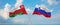 two crossed flags Slovenia and Oman waving in wind at cloudy sky. Concept of relationship, dialog, travelling between two