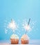 Two cupcakes decorated with sparklers, copy space