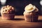 two cupcakes with frosting and a flower on top of them on a table with a blurry background