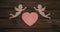 Two cupids and a heart made from wood texture background.