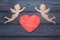 Two cupids and a red heart made of wood texture.