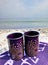 Two cups on a blanket on the beach.