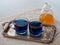 Two cups of blue butterfly pea flower tea, set on a silver tray and a jar of honey