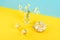 Two cups of camomile tea, transparent teapot and vase with daisy-like flowers on blue yellow background. Chamomile Tea