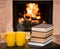 Two cups of coffee with books on the background of the fireplace
