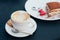 Two cups of coffee and tiramisu on black table background with beautiful latte art heart shaped.