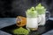 Two cups Dalgona Matcha Latte, a creamy whipped matcha, on dark background