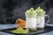 Two cups Dalgona Matcha Latte, a creamy whipped matcha, on dark background