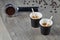 Two cups of espresso with chopsticks for blending on the background holder ground coffee. Biodegradable packaging