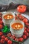 Two cups filled with fresh homemade tomato soup on a wooden plate with a variety of ripe tomatoes