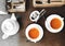 Two cups of healthy herbal tea with sea-buckthorn, ginger and honey on a textured light wooden table in a cafe with modern trendy
