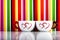 Two cups with hearts on colorful stripes background