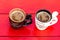 Two cups of homemade expresso coffee on red wooden board
