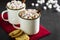 Two cups of hot chocolate, cocoa or warm drink with marshmallows and sweet cookies on dark background