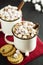Two cups of hot chocolate, cocoa or warm drink with marshmallows and sweet cookies on dark background