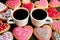 Two cups of hot coffee among heap of homemade heart shaped royal icing cute patterned cookies