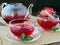 Two cups of pomegranate tea and glass tea pot with mint leaves