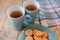 Two cups of tea on a blue napkin. Biscuits on a blue plate on a wooden background