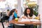 Two curly dark-haired sisters sitting at the table and studying together