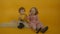 Two curly smiling kids sitting on carpet with lollipops