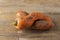 Two curved ugly carrots with pieces of soil on brown old wooden background. Vegetables with unusual strange shape