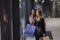 Two cute adolescent young women shopping on a cold winter evening, while holding large shopping bags