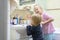 Two cute adorable blond caucasian siblings washing face and cleaning tooth with toothbrush at bathroom at home in