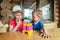 Two cute adorable caucasian blond little sibling sitting at table home yard and have fun tasting mom homemade fruit icecream.