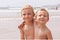 Two cute adorable little brothers boys sitting on the beach ocean sea