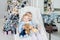 Two cute adorable little siblings brother and sister sitting in chair near christmas tree in cozy living room looking , dreaming