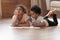 Two cute african kids playing drawing together on warm floor