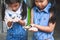 Two cute asian child girls holding black caterpillar