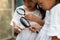 Two cute asian child girls using magnifying glass watching and learning on grasshopper that stick on hand with curious and fun