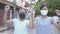 Two cute asian girls wearing protective face mask enjoy to practice lovely dance during standing on the pathway.