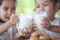 Two cute asian little child girls holding glass of milk