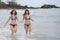 Two cute asian woman in bikinis are walking along the beach