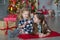 Two cute awesome girls sisters celebrating New Year Christmas close to xmas tree full of toys in stylish dresses with candies