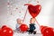 Two cute babies in fancy clothes, posing with red balloons. The concept of Valentine`s day and romance