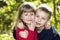 Two cute blond funny happy smiling children siblings, young boy brother embracing sister girl outdoors on bright sunny green bokeh