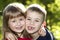 Two cute blond funny happy smiling children siblings, young boy brother embracing sister girl outdoors on bright sunny green bokeh
