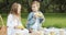 Two cute children girl and boy eating corn cobs and having fun together on a picnic in the park