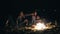Two cute couples embracing each other and sitting by the bonfire late at night looking at the stars